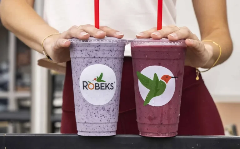 Two Robeks smoothies, one purple and one berry red, held side by side