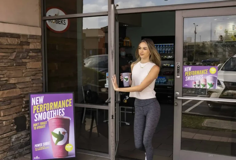 Customer leaving a Robeks store with a purple smoothie in hand