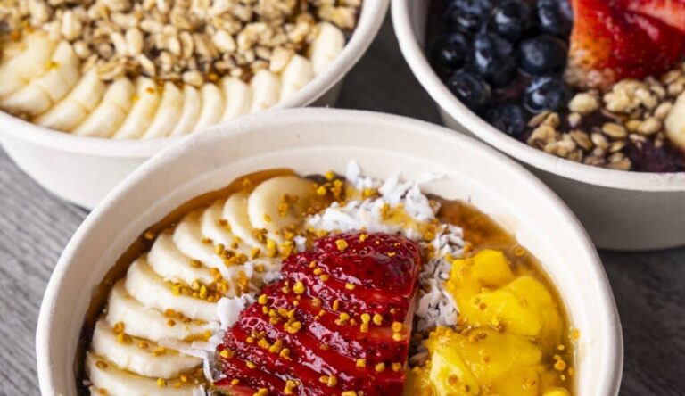 Colorful Robeks bowls topped with banana, strawberries, mango, blueberries, granola, and coconut