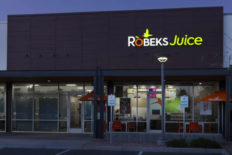 Robeks Juice storefront at night with illuminated signage and outdoor seating